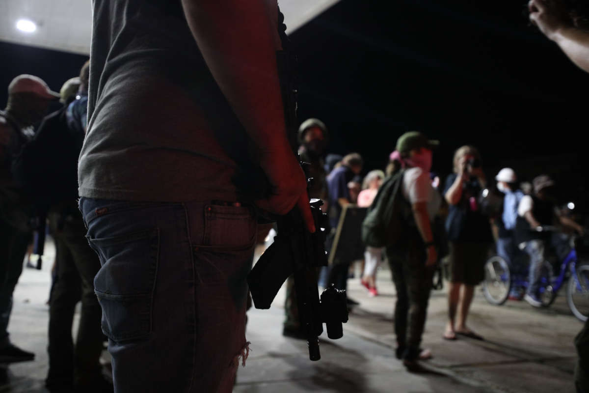 an armed man stands with a bunch of other armed men at a gas station in Kenosha, Wisconsin