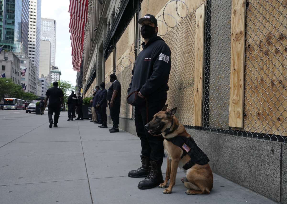 Private security guards with specially trained dogs stand in front of a boarded up and razor wired Saks Fifth Ave amid protests against the death of George Floyd on June 3, 2020, in New York City.