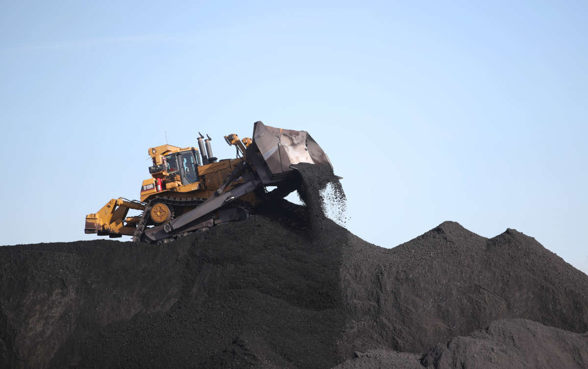 A worker moves coal around with a bulldozer