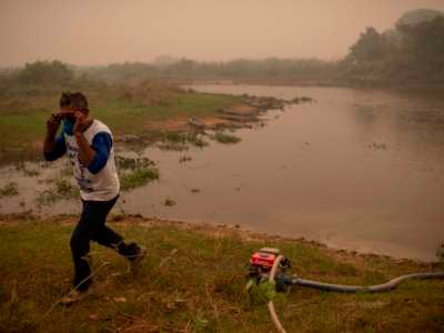 Volunteer Antonio Jose da Silva, 50, collects water from a river beside alligators to combat a wildfire as he and other volunteers try to protect a wooden bridge in Mato Grosso state, Brazil, on September 14, 2020.