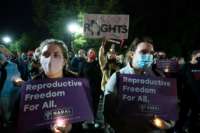 People hold signs supporting reproductive justice at a candlelight vigil