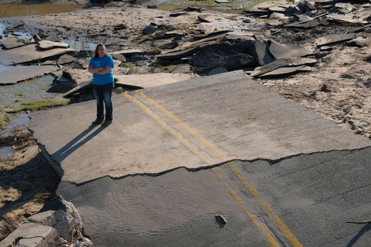 A woman stands on asphalt rubble of what was once a road