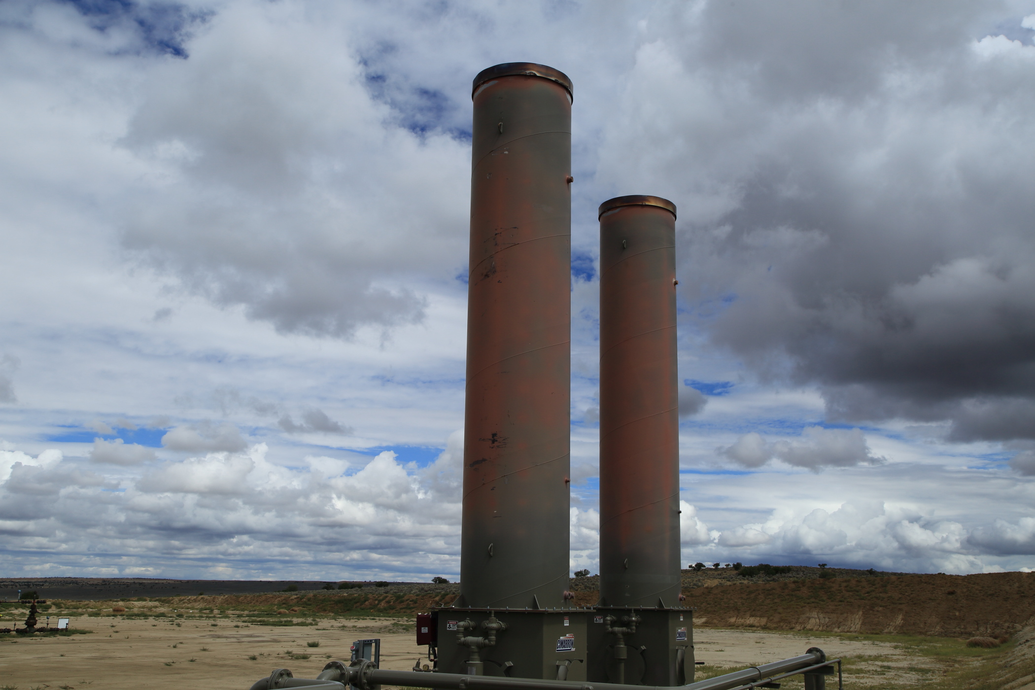 Smokestacks at a frack well installation, tinted red by high temperature gases, thrust above landscape of Greater Chaco in the Counselor Chapter of the Navajo Nation's Eastern Agency in New Mexico.