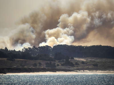 Smoke rises from the CZU Lightning Complex fire burning behind Davenport, California, in a view from Pigeon Point, on August 21, 2020.
