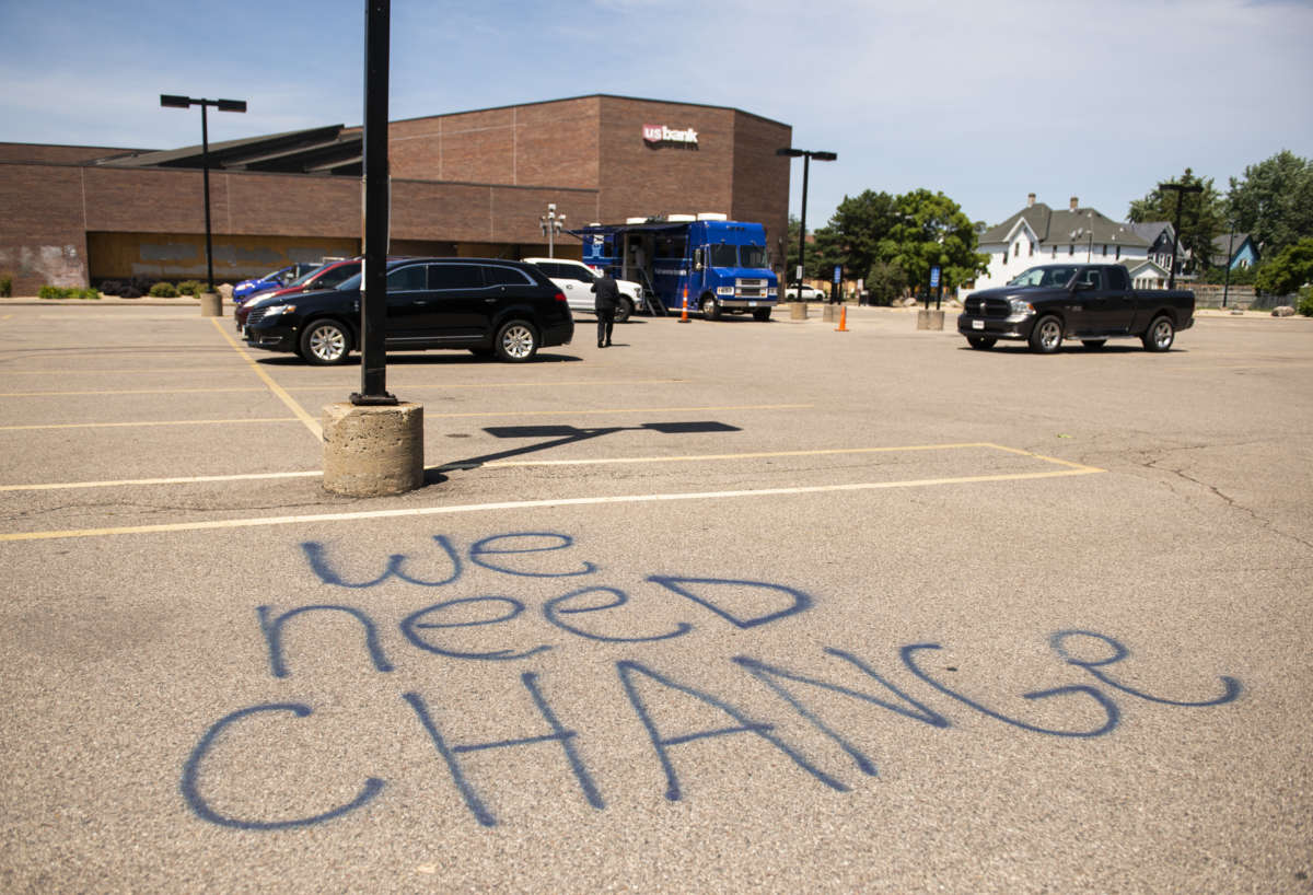 "WE NEED CHANGE" is spraypainted on the concrete of a U.S. Bank parking lot