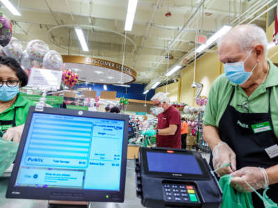 A cashier and bagger wear PPE at a Publix in Miami Beach, Florida, May 8, 2020.