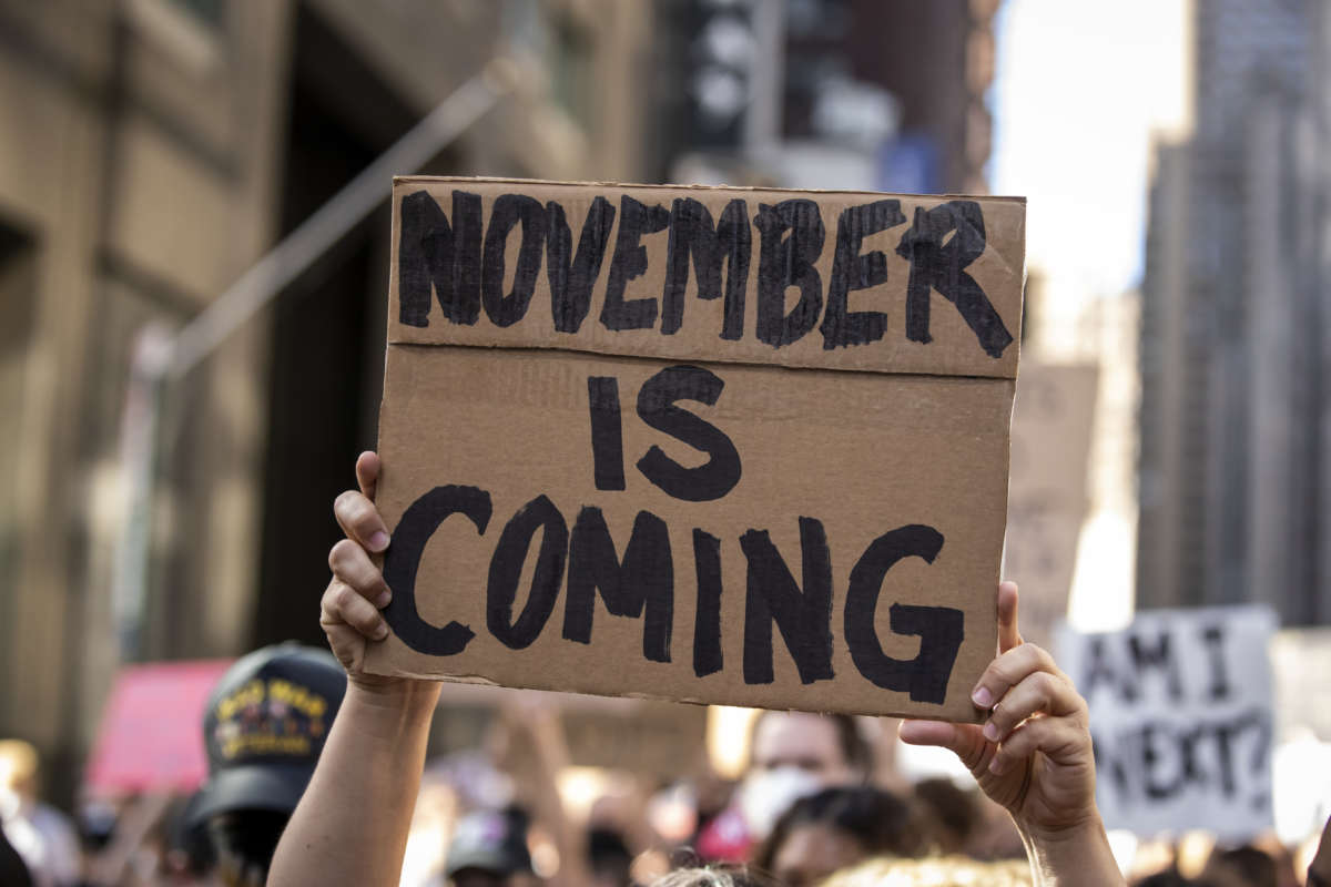 A protester holds a sign reading "NOVEMBER IS COMING" during a protest