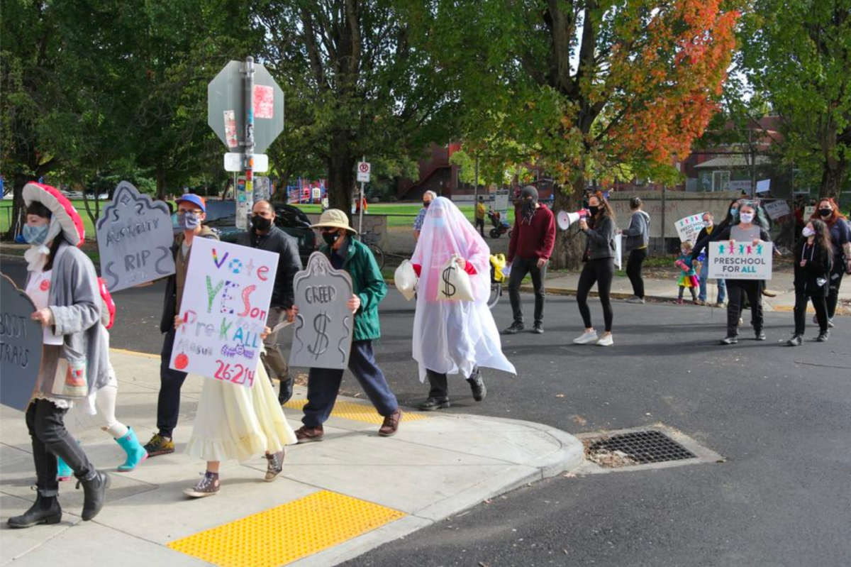 A parade marches in support of Measure 26-214, demanding tuition-free preschool.
