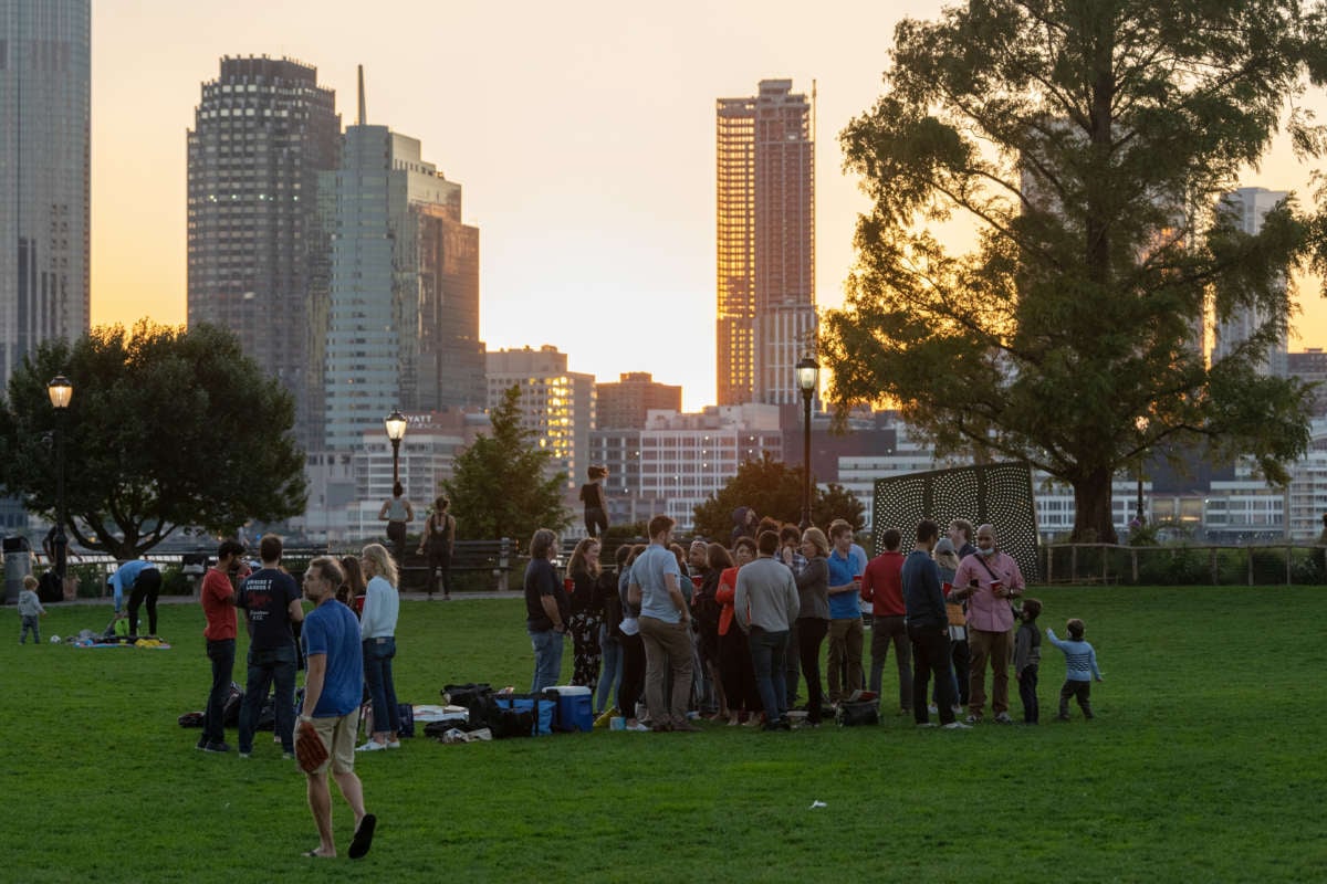 A group of people without masks avoid social distancing at Rockefeller Park during sunset as the city continues Phase 4 of re-opening following restrictions imposed to slow the spread of coronavirus on September 30, 2020, in New York City.