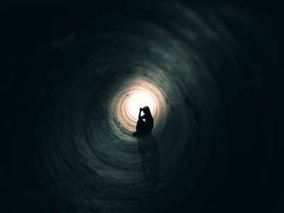 A person prays in dark pipe, tunnel