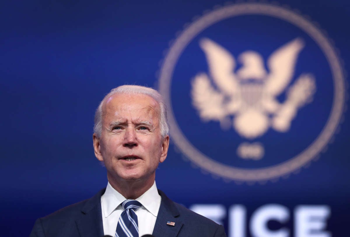 Joe Biden stands in front of a blue backdrop