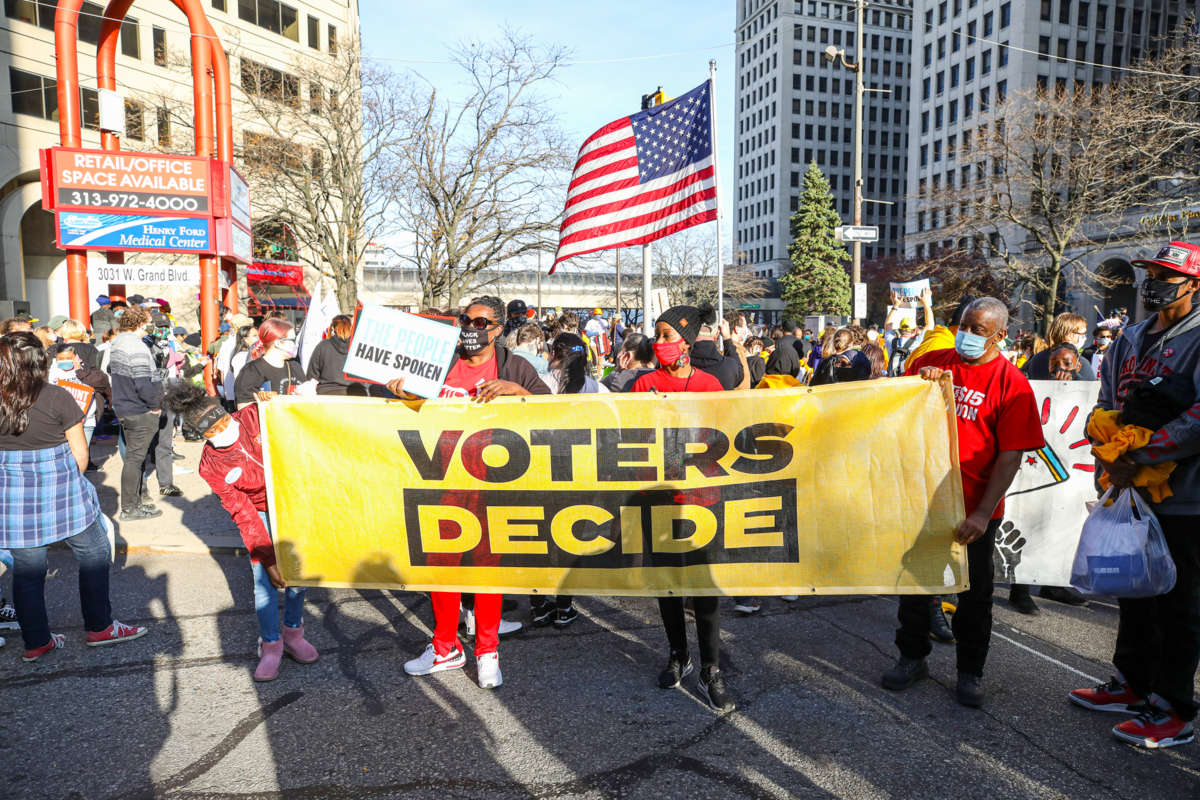 People march behind a banner reading "VOTERS DECIDE" during a protest