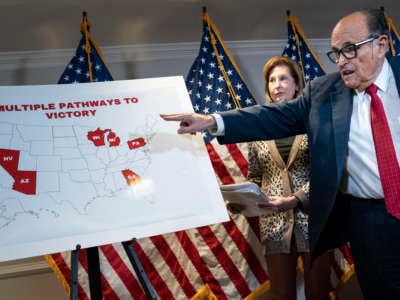 Rudy Giuliani points at a map as hairdye-stained sweat drips down his face