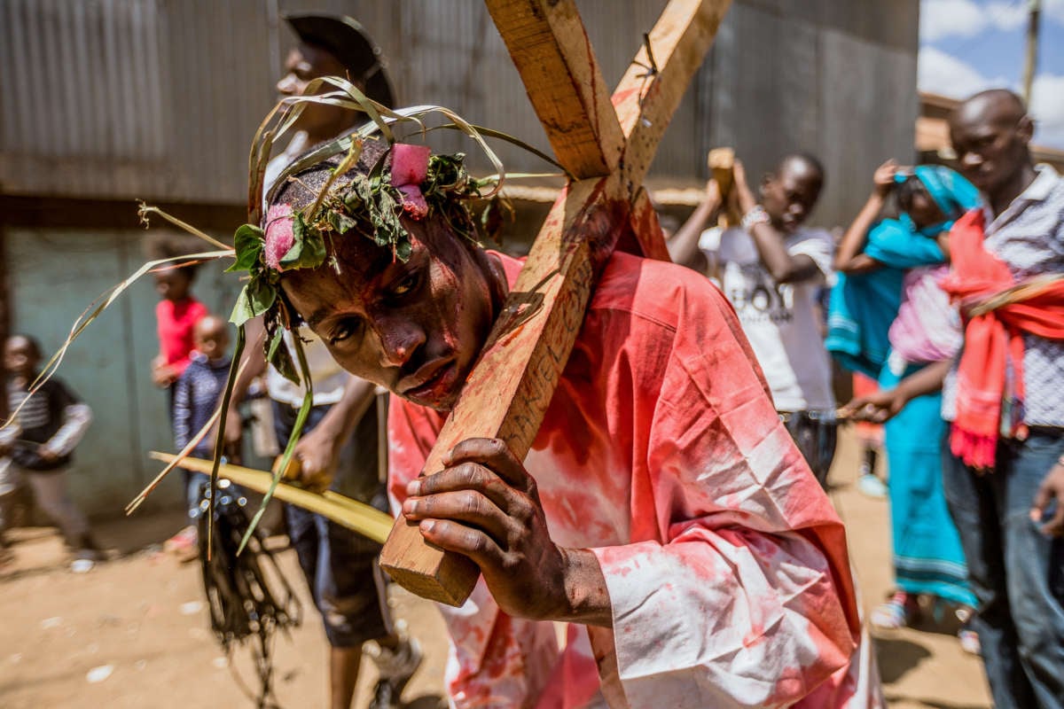 A bloodied man carries a cross