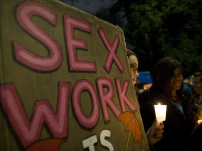 A protester holds a placard during a candle lit vigil to mark the International Day to End Violence Against Sex Workers in London on December 17, 2014.