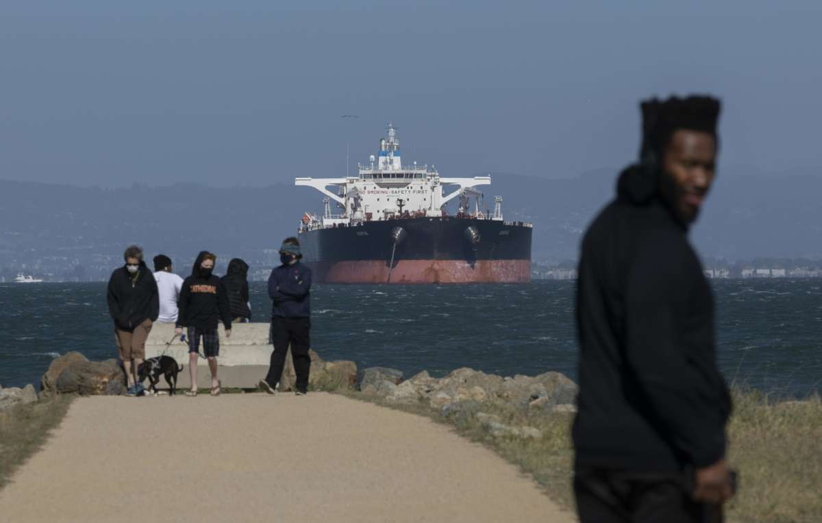 People enjoy sunshine as an oil tanker is berthed at San Francisco Bay amid the coronavirus outbreak on April 26, 2020, in San Francisco, California.