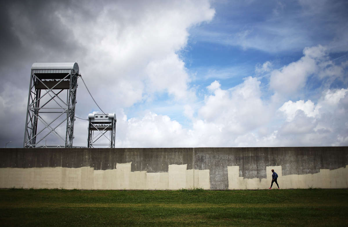 A person walks along the rebuilt Industrial Canal levee wall in the Lower Ninth Ward on May 18, 2015, in New Orleans, Louisiana.