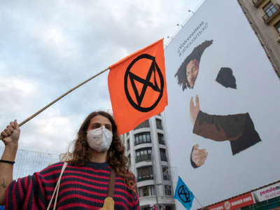 An activist wearing a face mask holds an extinction rebellion flag during a demonstration