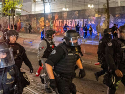 Portland police disperse a crowd of protesters past a mural of George Floyd and Breonna Taylor on September 26, 2020, in Portland, Oregon.