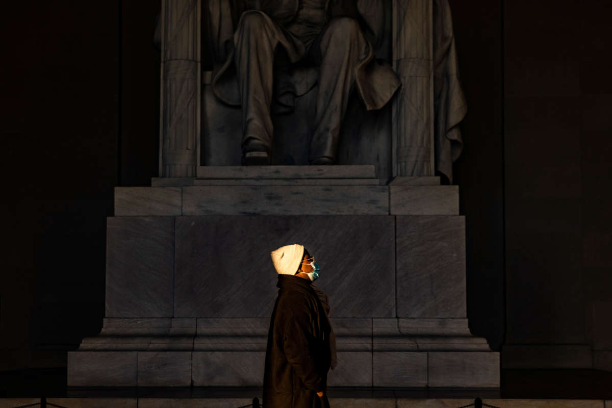 A woman stands in a beam of sunlight streaming into the Lincoln Memorial as the sun rises on December 27, 2020, in Washington, D.C.