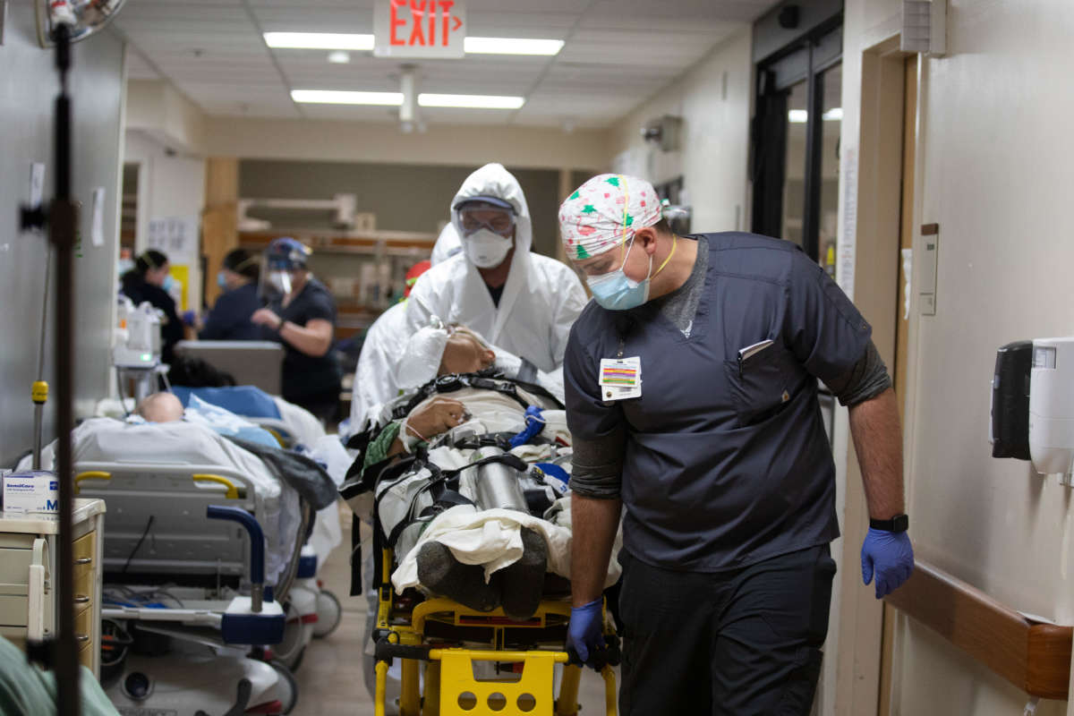 An ER tech helps the Mercy Air flight team transport a COVID-positive patient from the ED at Providence St. Mary Medical Center in Apple Valley, California on December 22, 2020, in Apple Valley, California.