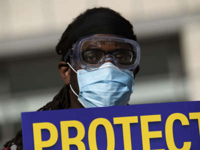 Dr. Salam Beah wears a face mask and carries a sign in support of resident physicians, interns and fellows at UCLA Health as they protest for improved COVID-19 testing and workplace safety policies outside of UCLA Medical Center in Los Angeles, California, December 9, 2020.