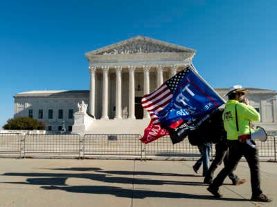A handful of Trump supporters carry flags in front of the U.S. Supreme Court on December 11, 2020.