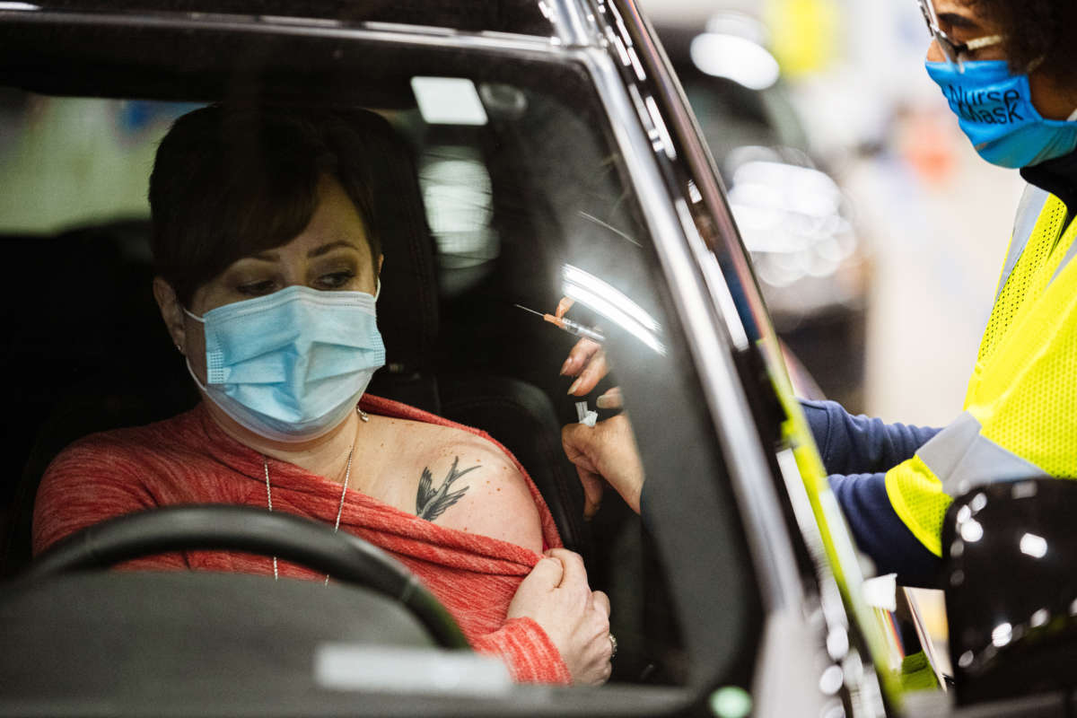 A health worker administers a vaccine to a patient in their vehicle during the first day of mass Moderna COVID-19 vaccinations in Broadbent Arena at the Kentucky State Fair and Exposition Center on January 4, 2021, in Louisville, Kentucky.