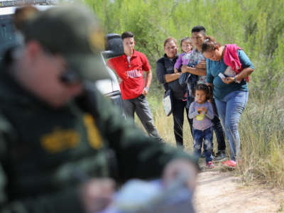 Central American asylum seekers wait as U.S. Border Patrol agents take groups of them into custody on June 12, 2018, near McAllen, Texas.