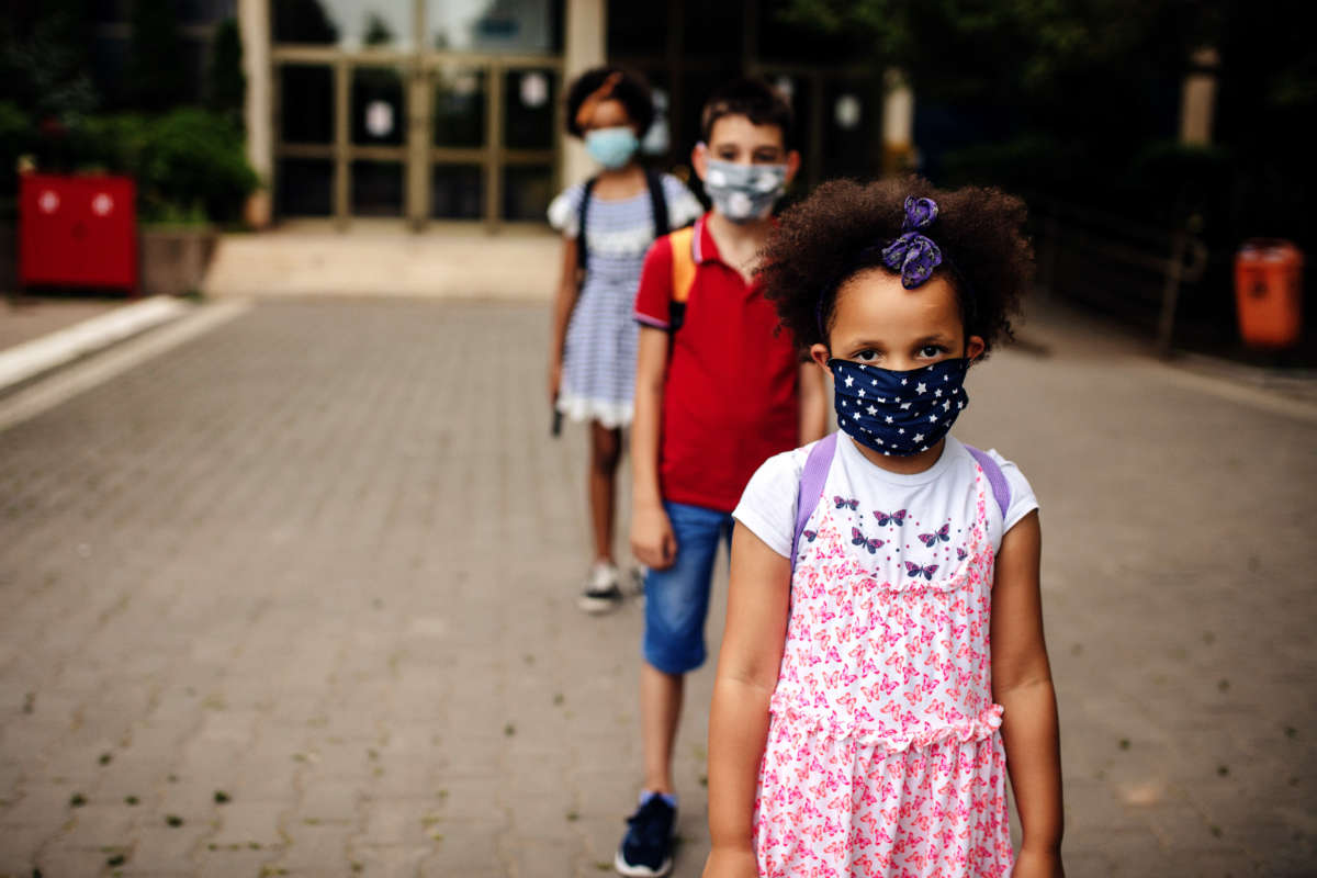 Young students with facemasks stand in a line