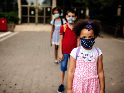 Young students with facemasks stand in a line