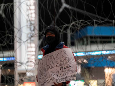 A migrant holds a sing reading "Biden: light the way for a humane immigration reform", as advocates and migrants demonstrate at San Ysidro crossing port during a vigil named "Path towards Humane Immigration Reform", in Tijuana, Mexico, on January 19, 2021.