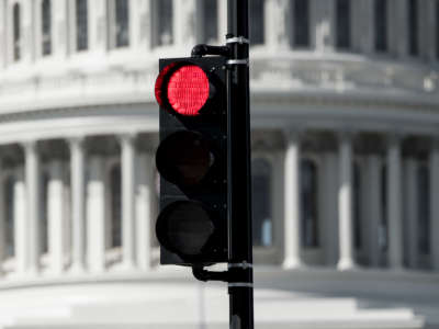 A red stoplight in front of the U.S. Capitol Building.