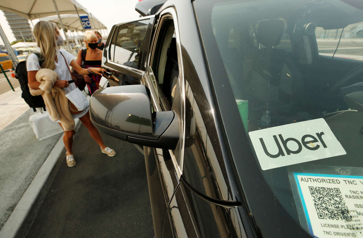 Passengers board into a car with an uber sticker