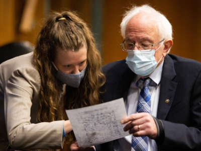Sen. Bernie Sanders confers with a Congressional staff member during a hearing on Capitol Hill in Washington, D.C., on January 27, 2021.