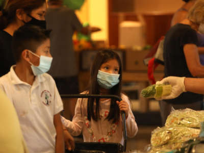 A volunteer talks with a young girl at the weekly food giveaway in the Fellowship Hall at Valley Park Church in North Hills, California, on October 14, 2020.