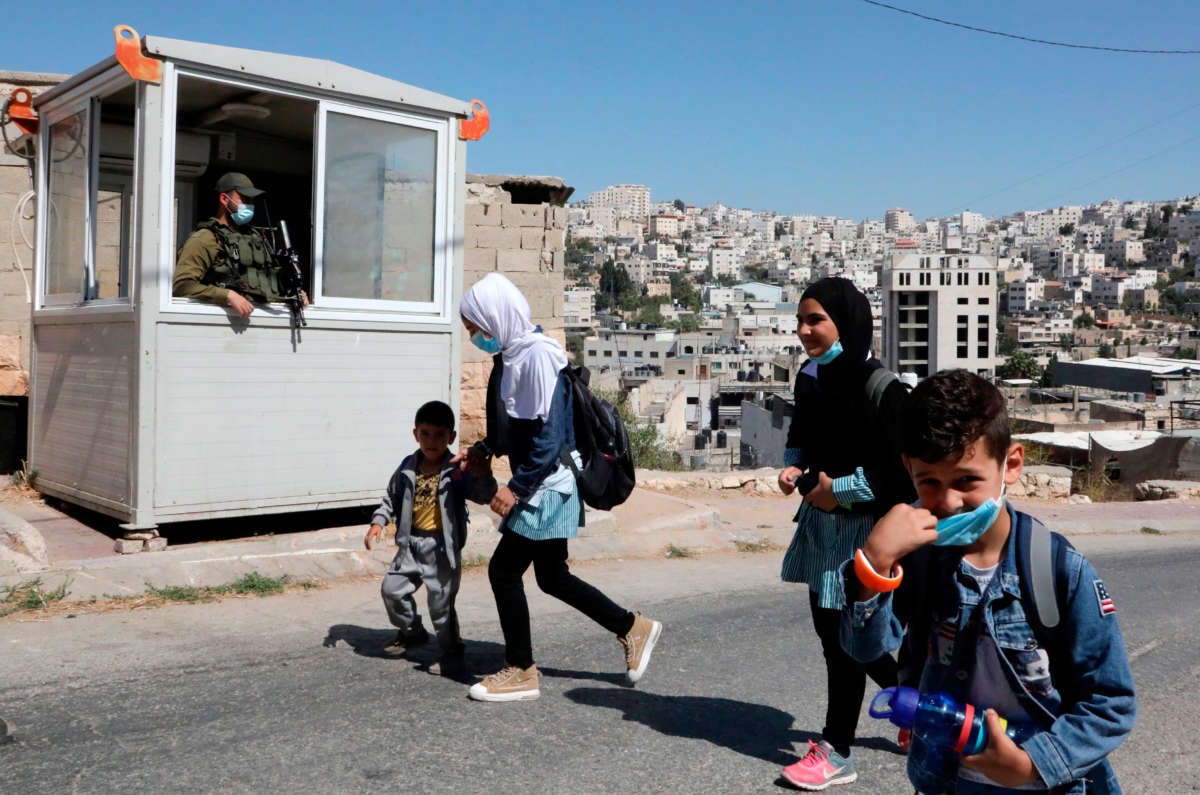 Palestinian children pass in front of an Israeli checkpoint as they walk to their house in Al-Shuhada Street, which is largely closed to Palestinians, in the city center of the West Bank town of Hebron, on September 24, 2020.