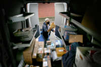 A postal worker puts mail into a truck
