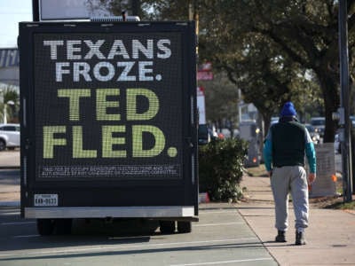 A pedestrian walks by a digital billboard truck with an image of Sen. Ted Cruz as it sits in a parking lot near Cruz's home on February 19, 2021, in Houston, Texas.