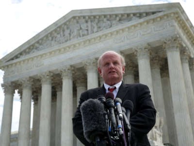 Michael Carvin speaks into a microphone on the steps of the united states supreme court