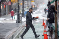 A waiter at Baby Brasa carries a tray of food towards an enclosed outdoor dining structure during a snow storm on February 7, 2021, in New York City.