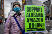 A woman holds a sign reading "SUPPORT ALABAMA AMAZON UNION" during a protest