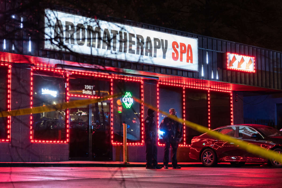 The exterior of a massage parlor at night is surrounded by police tape