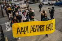 People march behind a banner reading "AAPI AGAINST HATE" during a protest