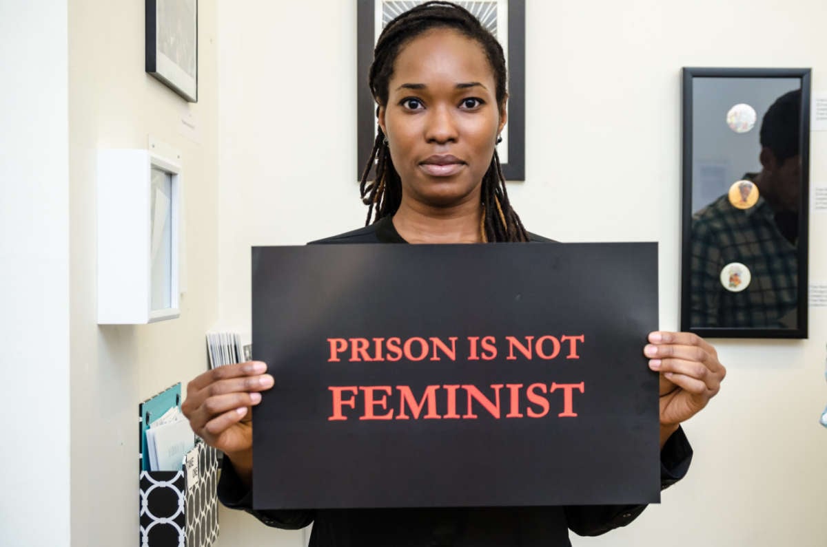 A woman holds a sign reading "PRISON IS NOT FEMINIST"