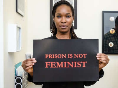 A woman holds a sign reading "PRISON IS NOT FEMINIST"