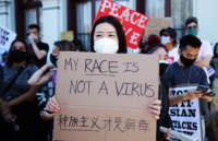 A woman holds a sign reading "MY RACE IS NOT A VIRUS" during a Stop Asian Hate protest