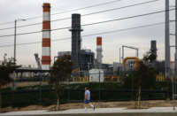 A man walks past a power plant looming in the background