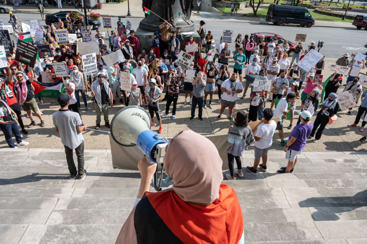 People chant and hold signs while listening to a speaker during a pro-Palestine protest on the steps of City Hall on May 23, 2021, in Louisville, Kentucky. Louisville Students for Justice in Palestine held the rally to decry Israel's recent military action in Gaza and to condemn the U.S. government's continued support of Israel.