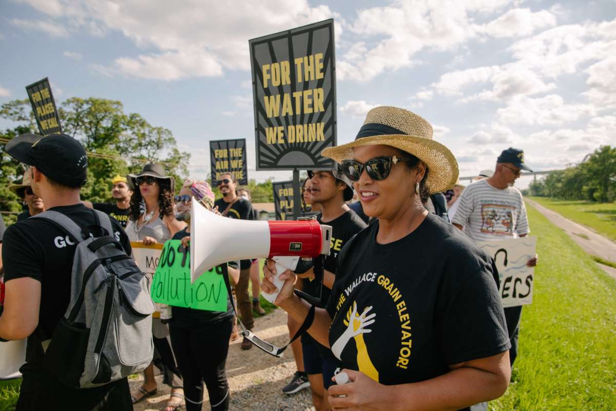 people display signs and speak into megaphones during an outdoor demonstration